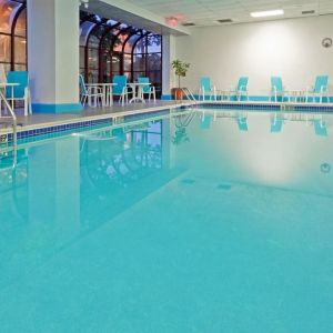 Indoor pool with seating area at Laguardia Plaza Hotel.