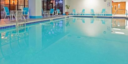 Indoor pool with seating area at Laguardia Plaza Hotel.