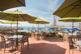 Outdoor seating with beach umbrellas at Hotel Delfin PV Beach Resort.