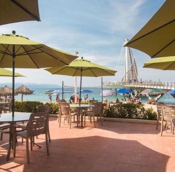 Outdoor seating with beach umbrellas at Hotel Delfin PV Beach Resort.