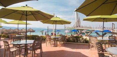 Outdoor seating with beach umbrellas at Hotel Delfin PV Beach Resort.