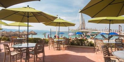 Outdoor seating with beach umbrellas at Hotel Delfin PV Beach Resort.