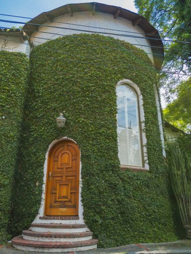 A short, rounded tower covered in ivy with an old wooden door.