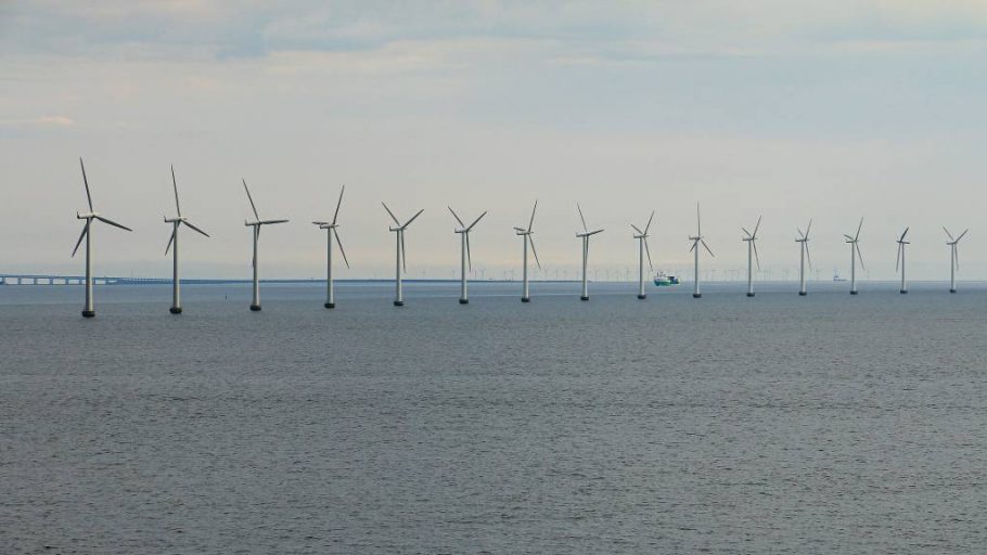 A danish offshore wind farm in Baltic Sea with ship passing in the distance.