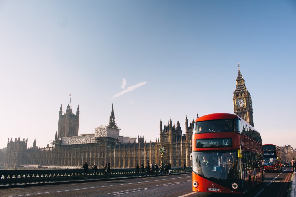 Iconic London double bus on a clear day with Big Ben, aka Elizabeth Tower in the background. 