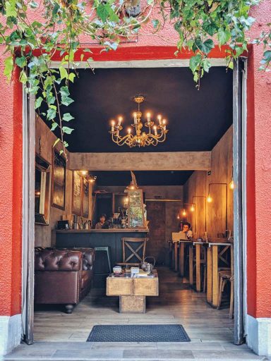 A brown leather coach and a golden chandelier decorate a beautiful coffee shop interior.