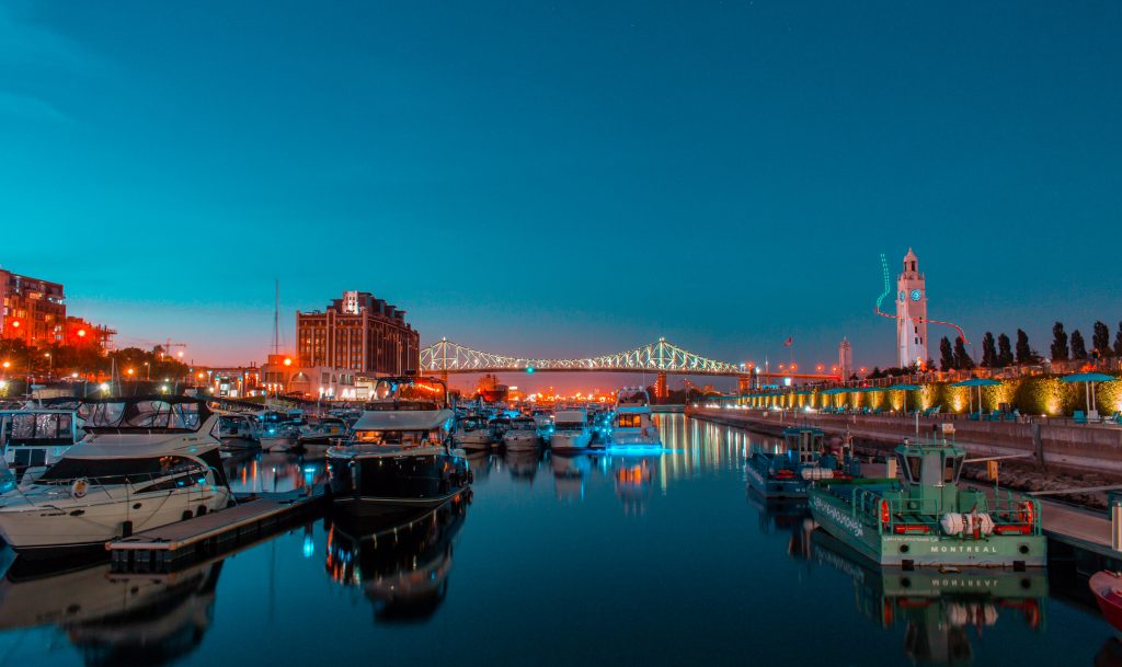 The Old Port of Montreal lit up against a blue sky evening.