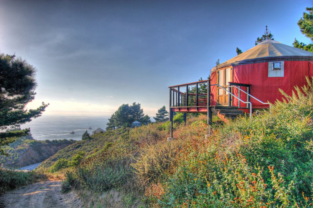 Red yurt overlooking trail, succulents and the Pacific Ocean.